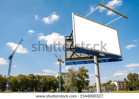 Blank white advertising billboard in front of construction site in the city