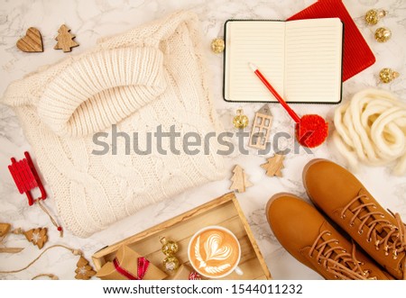 Top view over Christmas composition with warm sweater, gifts, xmas lights and coffee. Christas mood, slow living, indoor comfort concept