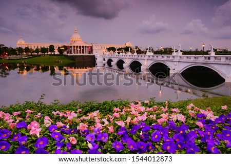 Spring Twilight Scenery of Olympus Bridge and Chimei museum  reflected in pond & bush clockvine blossoms and pink poui petals fall is traditional French Romanticism style. Tainan, Taiwan. Asia.