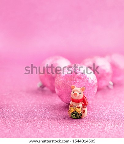 cute piggy toy and pink shiny Christmas balls close up on abstract pink background. pig - symbol of wealth, happiness and wellbeing in new year, lunar calendar. design for festive greeting card.