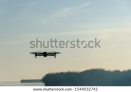 Drone copter with digital camera, blur river on background. Modern technology, UAV concept. Beautiful outdoor non urban scenery.
Drone flying over foggy day on the lake with digital camera