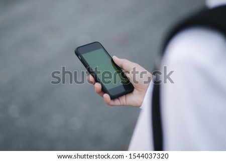 Mock up of teenage boy with wireless headphones use phone otside. Green screen