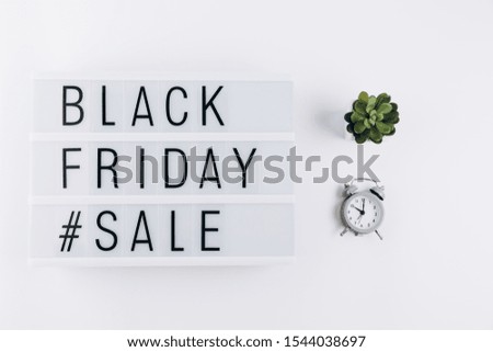 Creative Top view flat lay promotion composition with alarm clock and Black friday sale text on lightbox white background copy space