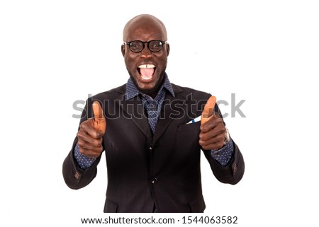 Handsome young businessman in suit standing on white background gesturing with thumbs and looking at the camera shouting with joy.