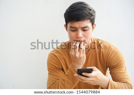 close up young teenager man bite finger while reading negative comment on social media or website or blog with stress feeling for cyber bulling and fake news concept Royalty-Free Stock Photo #1544079884