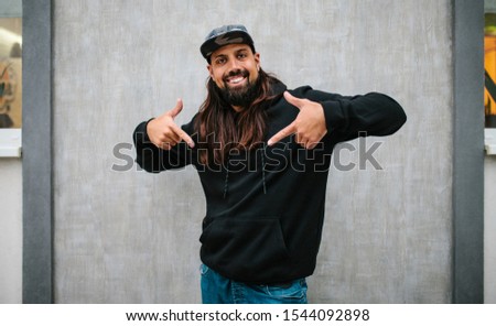 City portrait of handsome hipster man with beard wearing black blank hoodie or hoody with space for your logo or design. Mockup for print