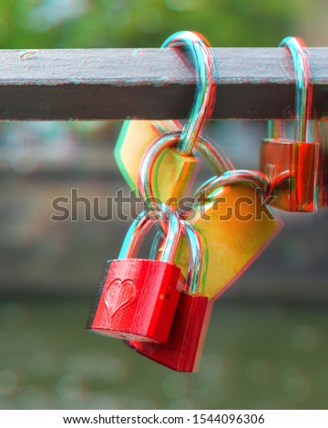 Locks on metal bridge railing over green water with green trees behind, 3D anaglyph effect