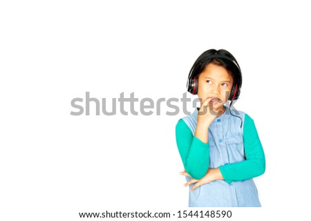 Asian pretty little girl in green shirt listening music in headphones and singing on white background. Charming girl in shorts and earphones inner thinking with lyric and copy space for wording.