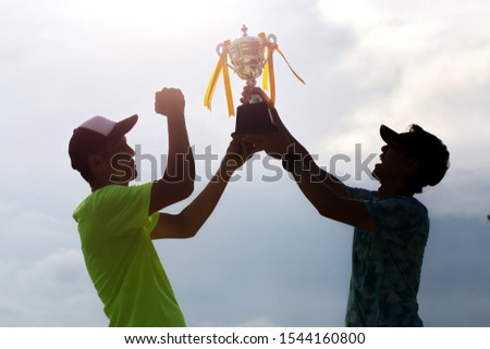 Two athletes are lifting the cup of success.