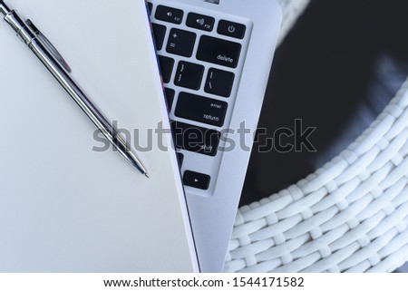 Blank white open  notebook with ballpoint pen on laptop computer on table, top view, close up