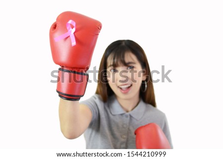 Asian woman is wearing red boxing gloves and having pink ribbon (breast cancer symbol) on white isolated background