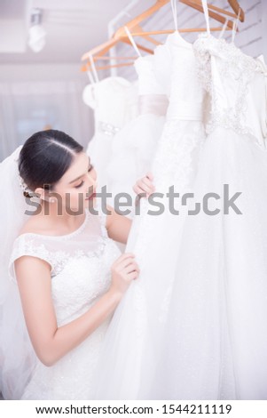 Asian young woman bride trying on wedding dress at modern wedding