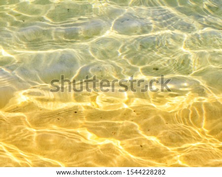 The surface of the water with highlights and shadows on a shallow sandy bottom in the morning tones creates a happy mood and makes you think about vacation.