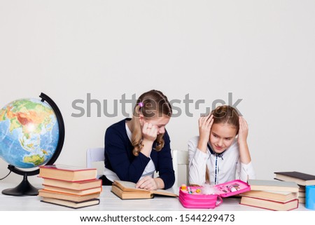 two schoolgirl girls at the desk in a geography class