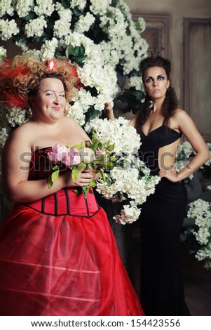 Two queens in carnaval dress. Black and red. Holiday picture.