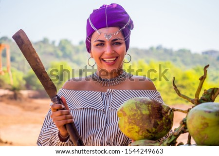 Happy african american woman opening cutting coconut with machete.indian girl open coco nut water in half with a big knife