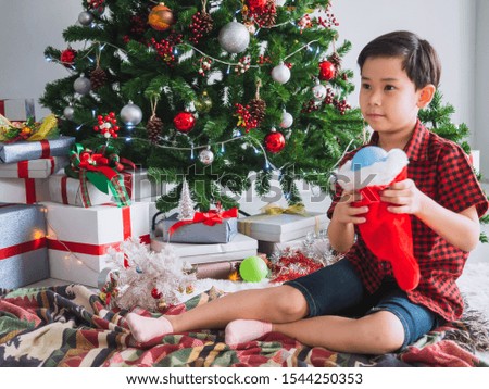 boy in a red shirt is happy and funny to celebrate Christmas with christmas tree