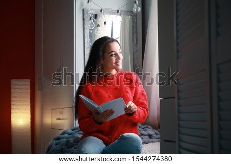 Young woman with book at home. Winter season