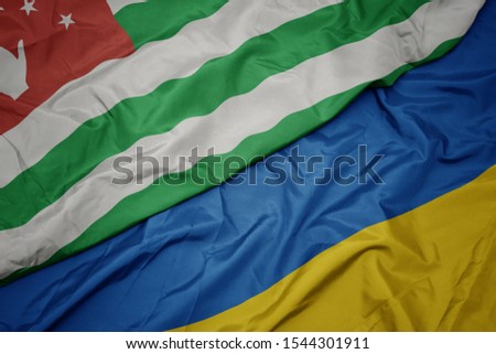waving colorful flag of ukraine and national flag of abkhazia. macro