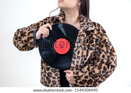 woman wearing tiger pattern clothes holding old vinyl retro record music audio on background