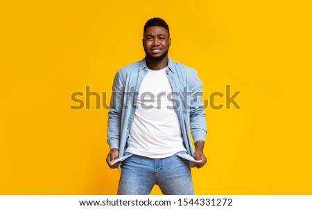 I'm broke. Desperate man showing empty turned out pockets over yellow studio background Royalty-Free Stock Photo #1544331272