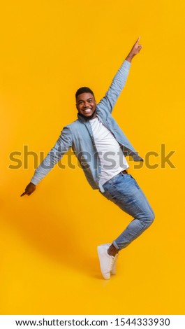 Cheerful Standing On Tiptoes, Fooling Over Yellow Background In Studio