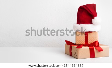 Conceptual Christmas composition of wrapped presents in Santa's hat on white background, panorama, copy space