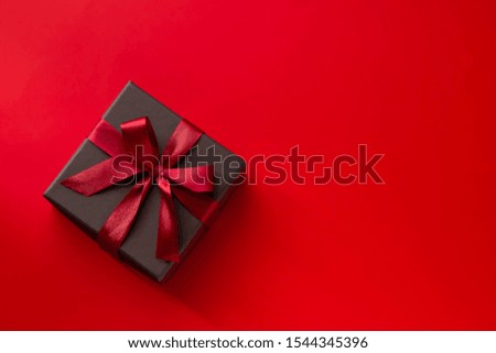 An image of a present in a gift box connected with a plain ribbon background and a red ribbon
