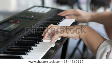 The pianist's finger is playing on the electone pad with blurred background, in concept of musician, electronic music instrument.