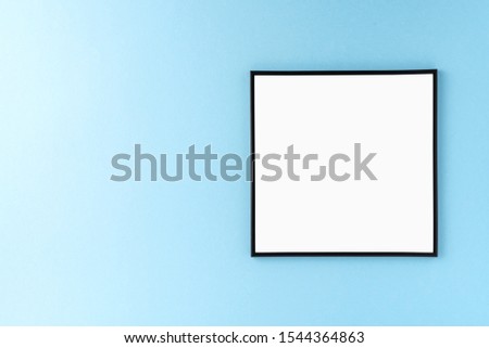 Mockup of empty picture frame on blue background with copyspace