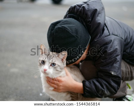 boy hugs a beautiful light cat on the street