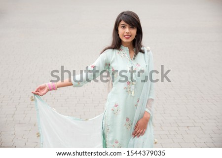 Portrait of an Indian young girl. Girl in traditional Indian clothing, salwar kameez. Girl traditional Indian decorations, bindi, chudiyan, jumka Royalty-Free Stock Photo #1544379035