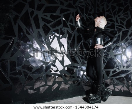 young blonde caucasian man standing in alien cosmos halloween costume and looking near the many mirrors and reflecting on black background