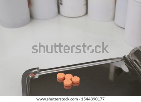 four orange medical tablets on half counting drug tray for drugstore