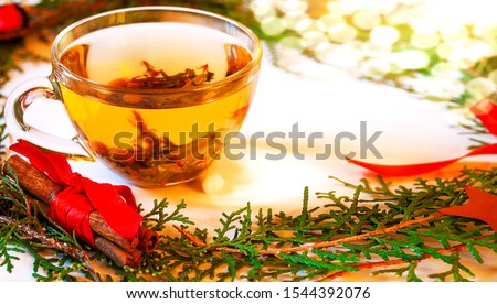 A transparent cup of herbal tea with cinnamon, sprigs of pine needles. Christmas background.  Royalty-Free Stock Photo #1544392076