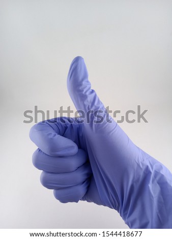 tumb up hand using medical puple hand glove 