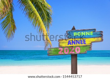 Bonne annee 2020, meaning happy new year in French, on direction signs, tropical beach background Royalty-Free Stock Photo #1544453717