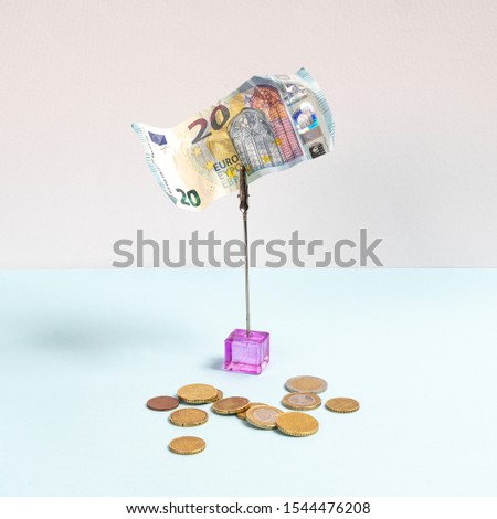 a twenty euro banknote and some coins on a colored surface