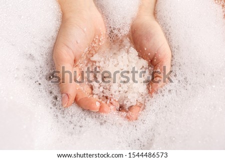 white bath salt in a female hand dissolves in water