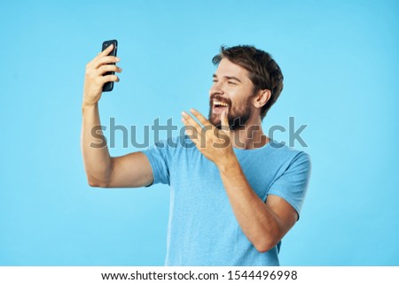 Handsome man in a blue T-shirt with a mobile phone in his hand, new technologies