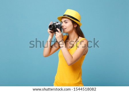 Traveler tourist woman in yellow summer casual clothes, hat with photo camera isolated on blue background. Female passenger traveling abroad to travel on weekends getaway. Air flight journey concept