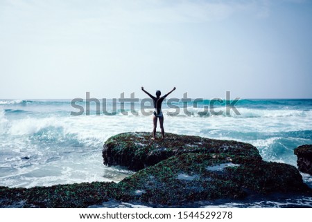 Freedom woman outstretched arms at seaside mossy coral reef