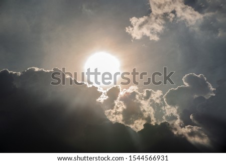 Beautiful evening skyscape. Sun's rays shine through hole in black clouds before rain, natural background. Inspirational concept.