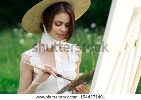 young woman in a summer white dress in a forest glade in a straw hat