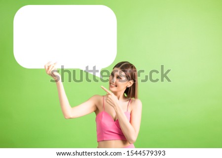 Asian woman holding and looking up to speech bubble with empty space for text on green background