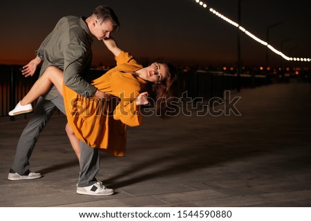 Beautiful young couple practicing dance moves in evening outdoors