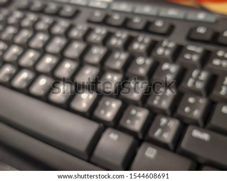 The blurred image of keyboard is black and the characters are white, placed on the table.