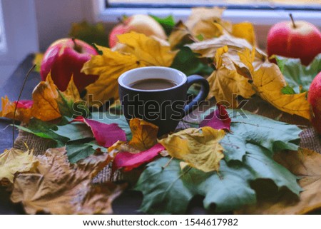 Cup of coffee, autumn leaves and red apples.