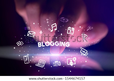 Finger touching tablet with drawn social media icons and BLOGGING inscription, social networking concept