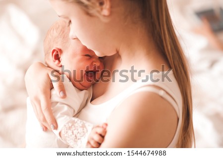 Young mother holding crying baby girl 6-8 months old in room closeup. Motherhood. Maternity.  Royalty-Free Stock Photo #1544674988